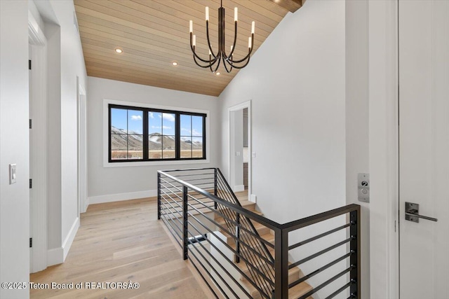 hallway featuring wood ceiling, baseboards, an upstairs landing, light wood-type flooring, and an inviting chandelier