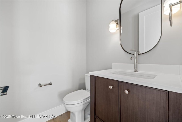 bathroom featuring baseboards, vanity, and toilet