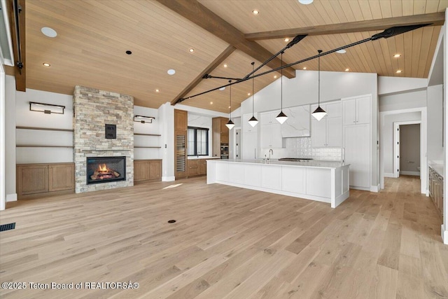 unfurnished living room featuring beam ceiling, a fireplace, light wood-style floors, high vaulted ceiling, and wooden ceiling