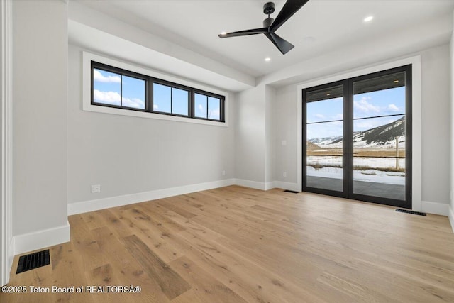 unfurnished room with light wood-type flooring, visible vents, and baseboards