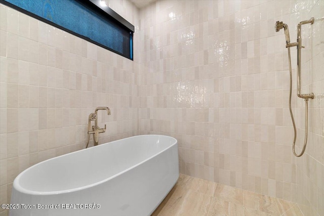 bathroom with a freestanding bath and tile walls