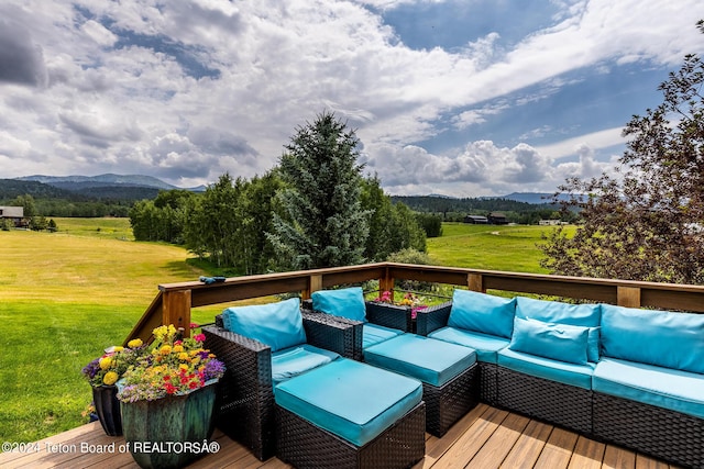 deck with a yard, outdoor lounge area, and a mountain view