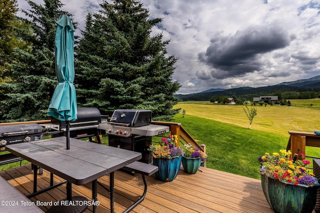 wooden deck with a mountain view and a yard