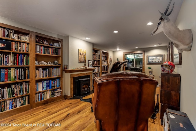 interior space with built in features, light hardwood / wood-style floors, and a wood stove