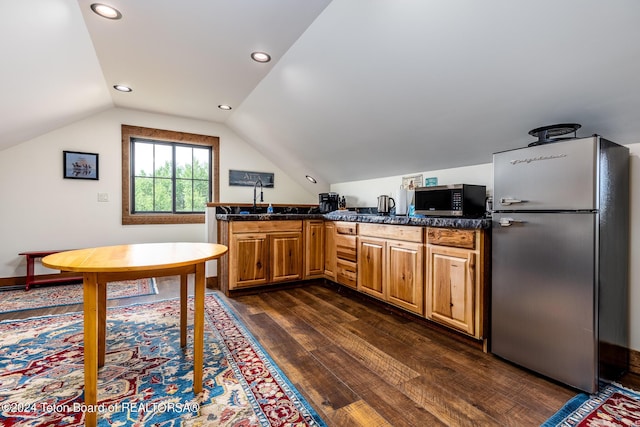 kitchen featuring sink, appliances with stainless steel finishes, dark hardwood / wood-style flooring, vaulted ceiling, and kitchen peninsula