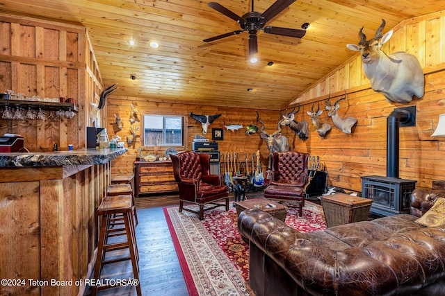 living room featuring lofted ceiling, a wood stove, dark wood-type flooring, and wood ceiling