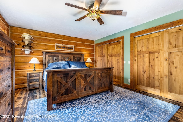 bedroom featuring two closets, dark hardwood / wood-style floors, and ceiling fan