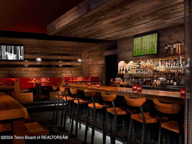 bar featuring wooden ceiling, a community bar, and wooden walls