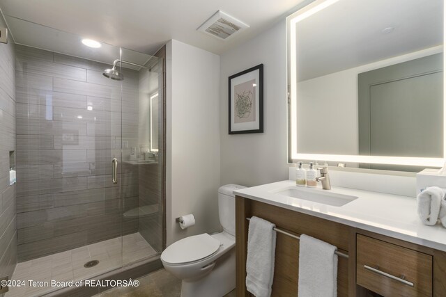 bathroom featuring vanity, tile patterned floors, toilet, and walk in shower