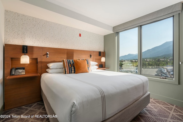 bedroom featuring a mountain view, dark carpet, and multiple windows