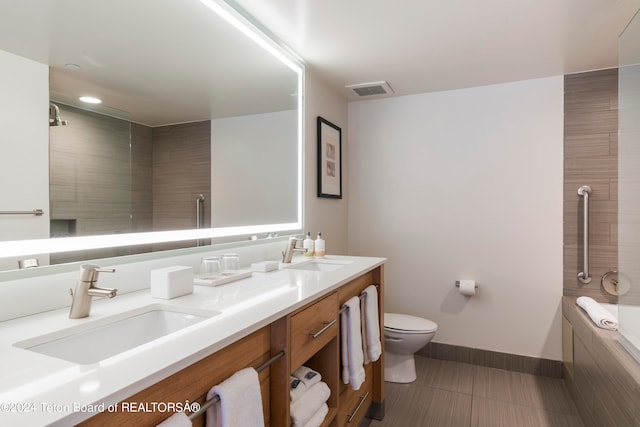 bathroom featuring tile patterned flooring, dual vanity, and toilet