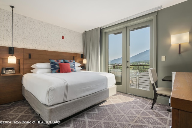 carpeted bedroom featuring a mountain view, wood walls, french doors, and access to exterior