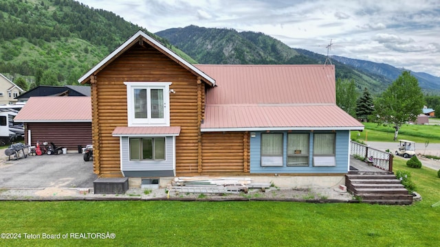 rear view of house featuring a mountain view and a yard