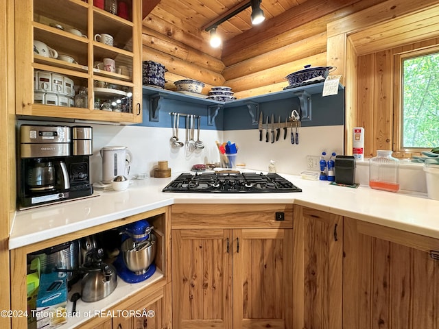 kitchen featuring wood ceiling, rail lighting, black gas cooktop, and rustic walls