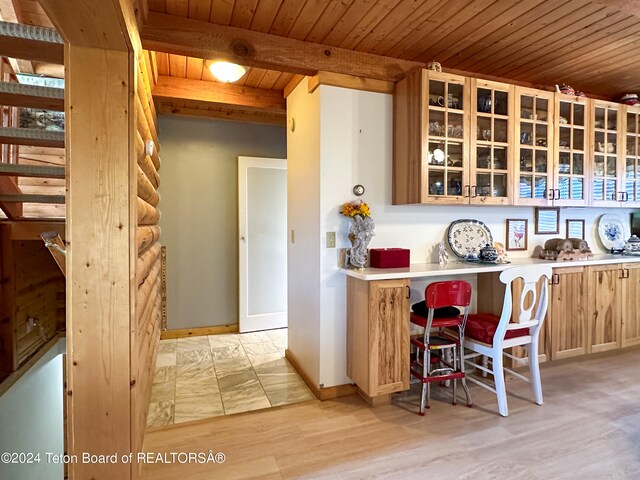 kitchen featuring wood ceiling, a kitchen bar, light hardwood / wood-style floors, and beam ceiling