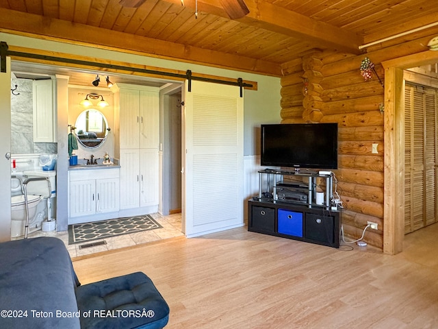 living room featuring log walls, beamed ceiling, a barn door, light wood-type flooring, and wooden ceiling