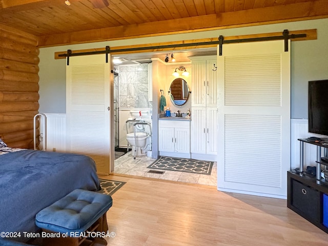 bedroom with hardwood / wood-style flooring, sink, a barn door, and wooden ceiling