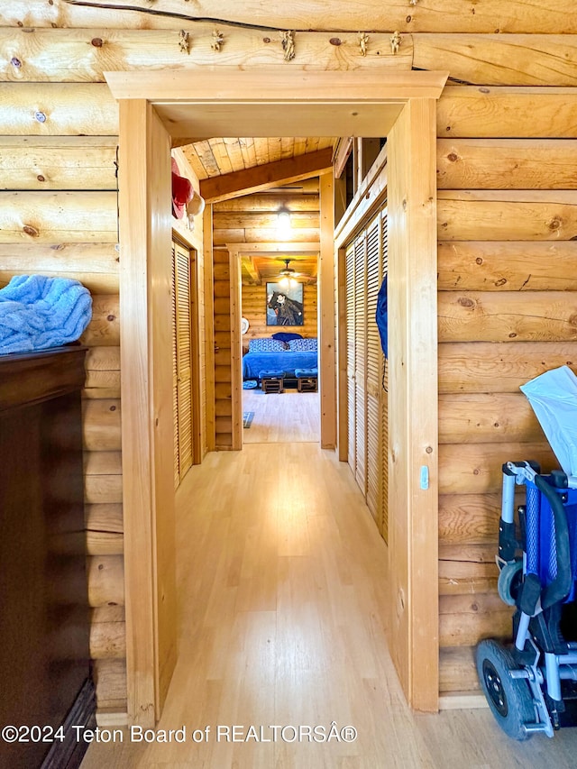 hallway featuring hardwood / wood-style floors, lofted ceiling with beams, and log walls