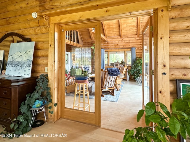 entryway with beam ceiling, hardwood / wood-style flooring, log walls, and wooden ceiling