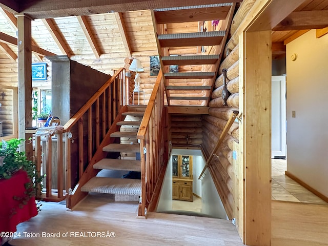 staircase featuring hardwood / wood-style flooring, vaulted ceiling with beams, wood ceiling, and rustic walls