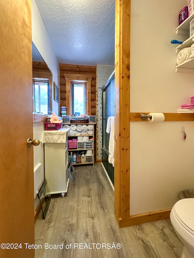 bathroom featuring wood walls, toilet, a textured ceiling, and hardwood / wood-style flooring