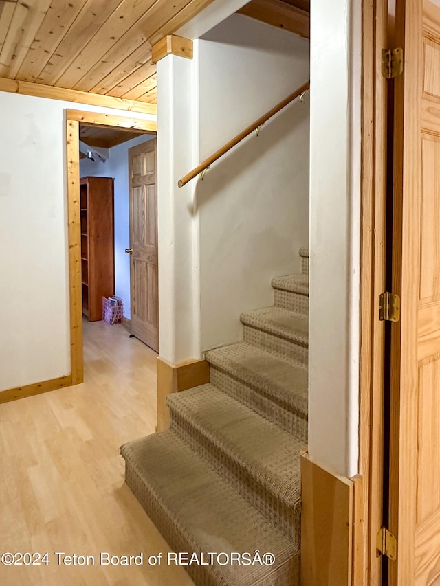 staircase with light hardwood / wood-style floors and wooden ceiling