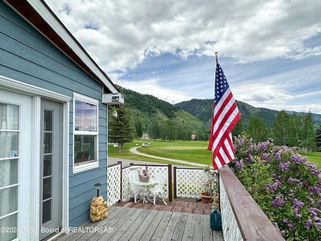 wooden deck featuring a mountain view and a yard