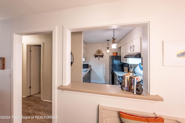 kitchen featuring white cabinets, decorative light fixtures, hardwood / wood-style floors, and black appliances