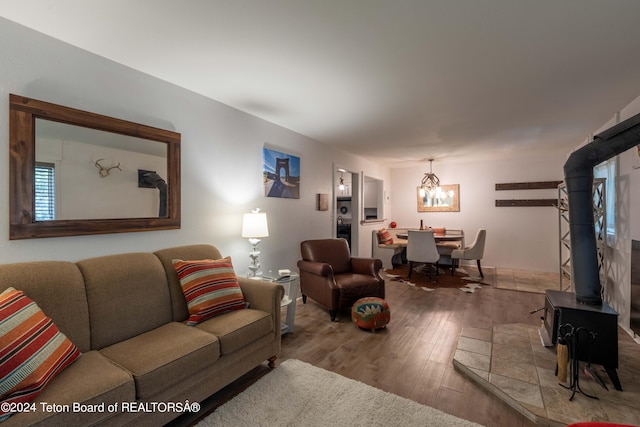 living room with an inviting chandelier, hardwood / wood-style floors, and a wood stove