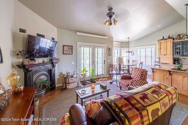 living room featuring lofted ceiling, a textured ceiling, wood-type flooring, and ceiling fan