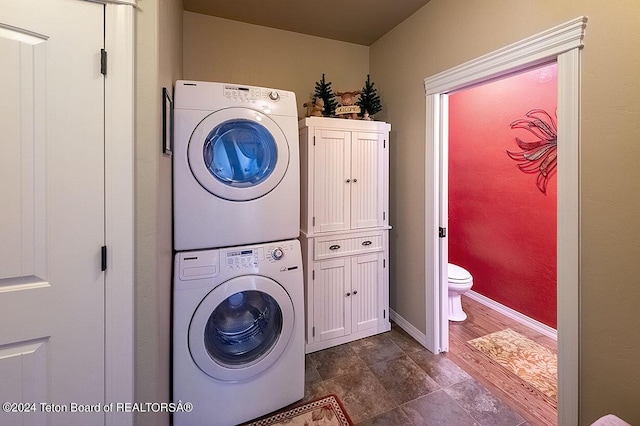 laundry room featuring cabinets and stacked washer and clothes dryer