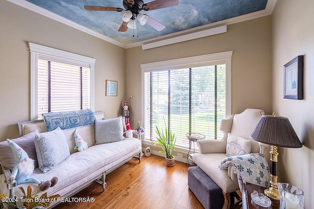 living room featuring hardwood / wood-style flooring, crown molding, and ceiling fan