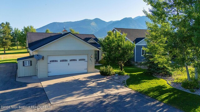 view of front facade featuring a mountain view, a garage, and a front lawn