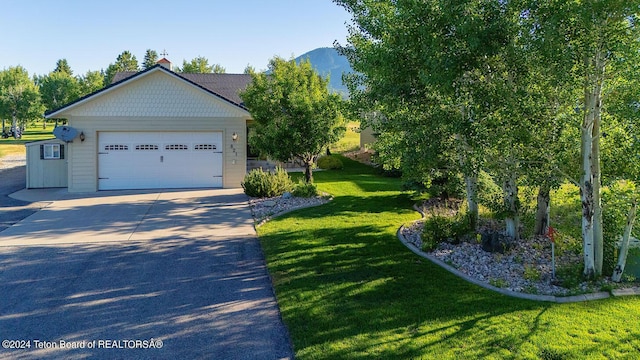 view of front of house featuring a garage, a mountain view, and a front lawn