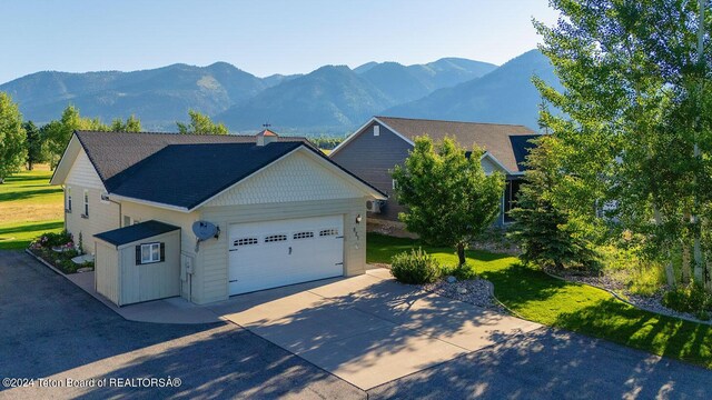 view of front of property with a garage, a mountain view, and a front lawn