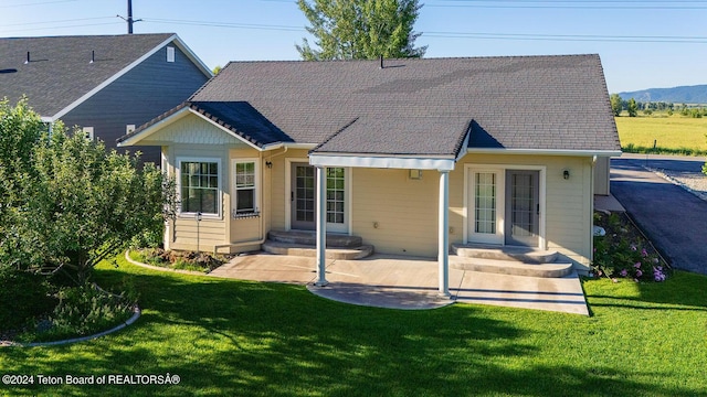 rear view of property featuring a mountain view, a patio area, and a lawn