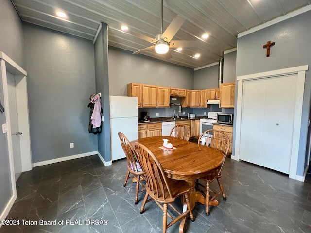 dining room with sink, ceiling fan, dark tile patterned flooring, and a high ceiling