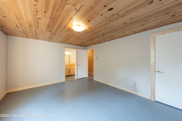 unfurnished room with baseboards, wooden ceiling, and finished concrete floors