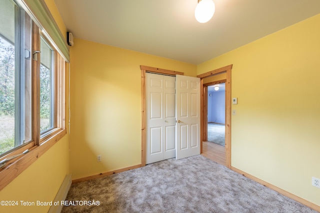 unfurnished bedroom with carpet, a closet, and baseboards