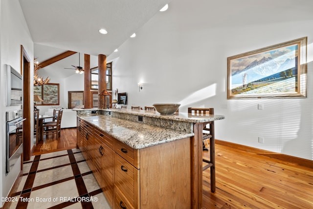 kitchen featuring hardwood / wood-style floors, a center island, stainless steel oven, and a kitchen bar