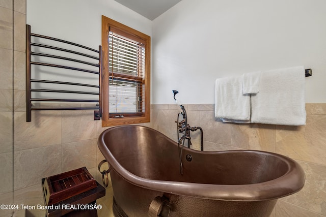 bathroom with sink, radiator, a bath, and tile walls