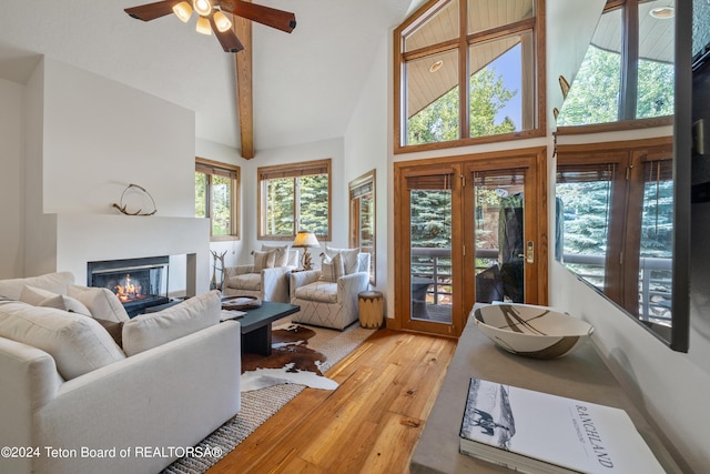 living room with ceiling fan, beam ceiling, high vaulted ceiling, and light hardwood / wood-style flooring