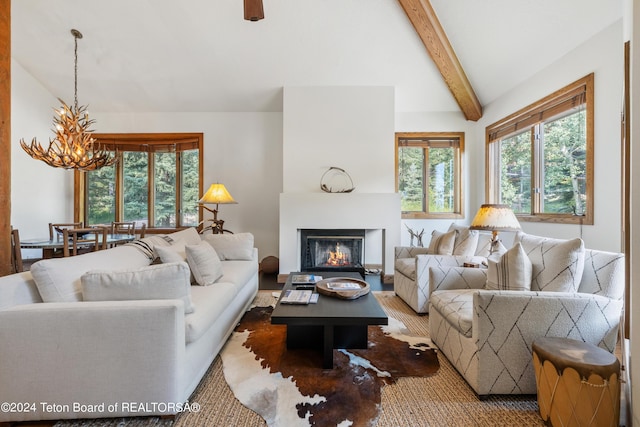 living room with lofted ceiling with beams and an inviting chandelier