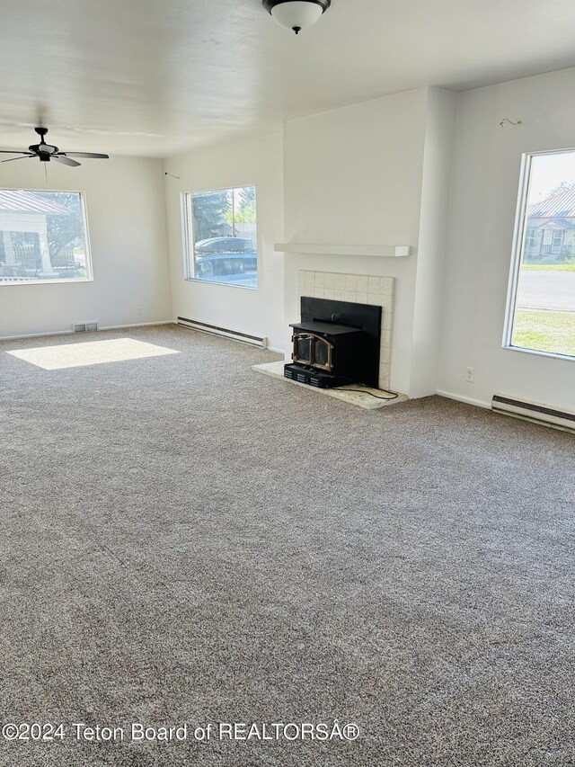 unfurnished living room featuring carpet, a tile fireplace, a baseboard radiator, and plenty of natural light