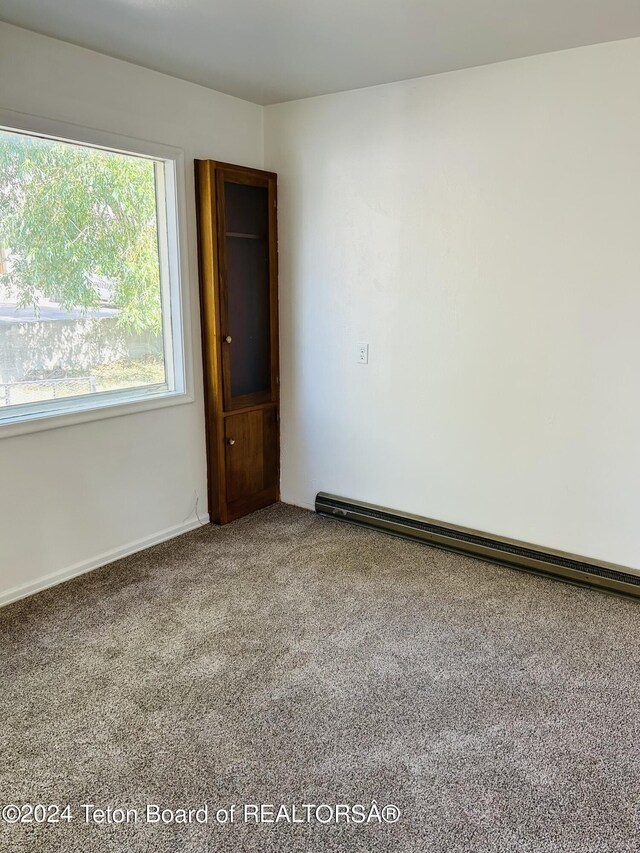 spare room featuring carpet floors and a baseboard radiator