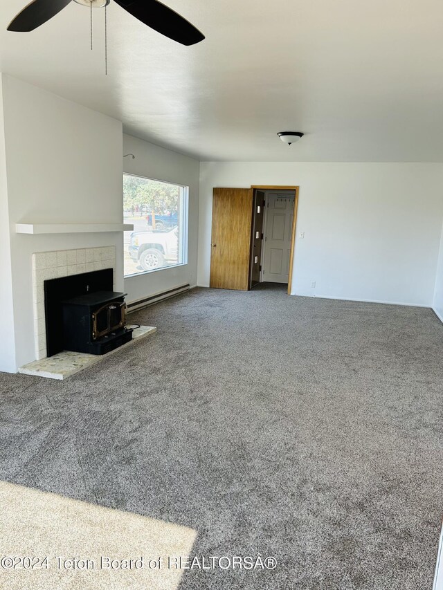 unfurnished living room with carpet, a fireplace, ceiling fan, and baseboard heating