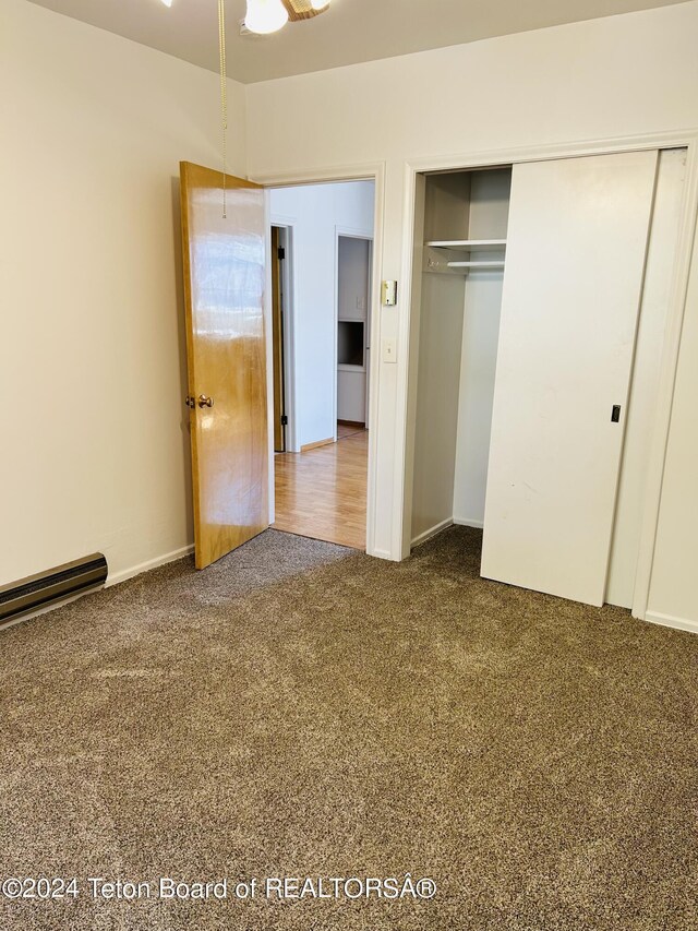 unfurnished bedroom featuring dark carpet and a closet