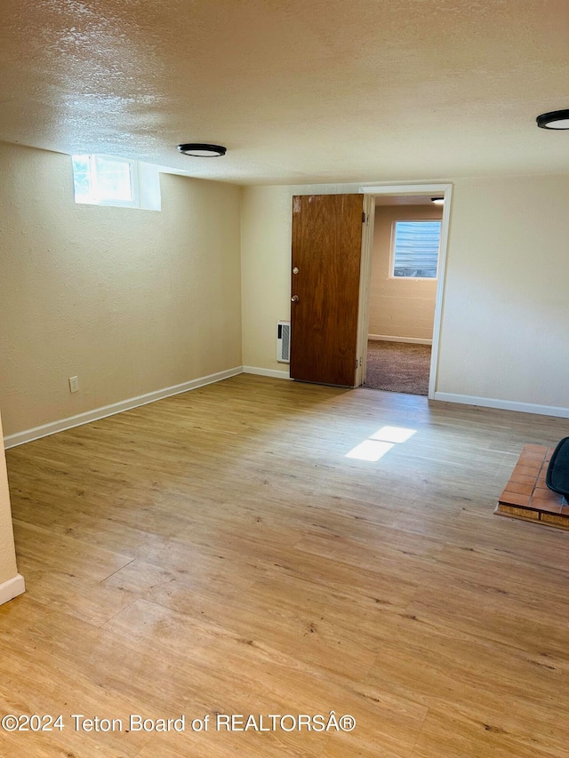 interior space with multiple windows, a textured ceiling, and light wood-type flooring