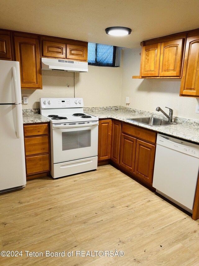 kitchen with sink, light hardwood / wood-style flooring, light stone counters, and white appliances