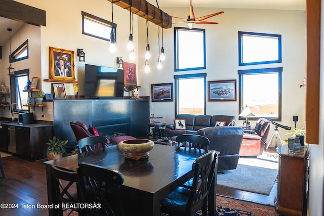 dining room featuring ceiling fan, dark hardwood / wood-style flooring, a fireplace, and a high ceiling